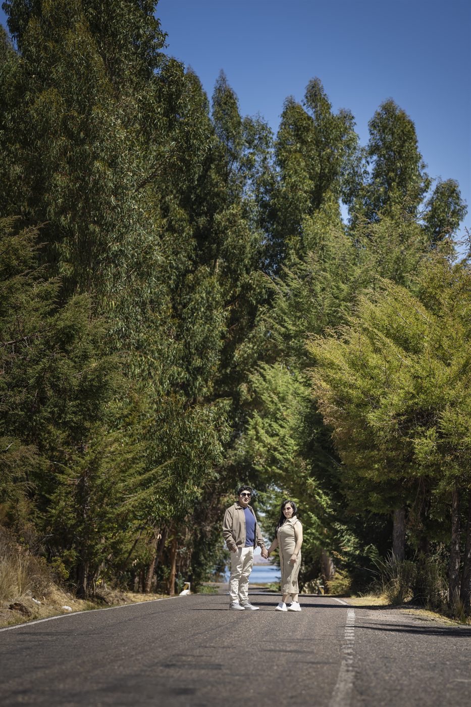 Los novios a lo lejos en un camino entre eucaliptos