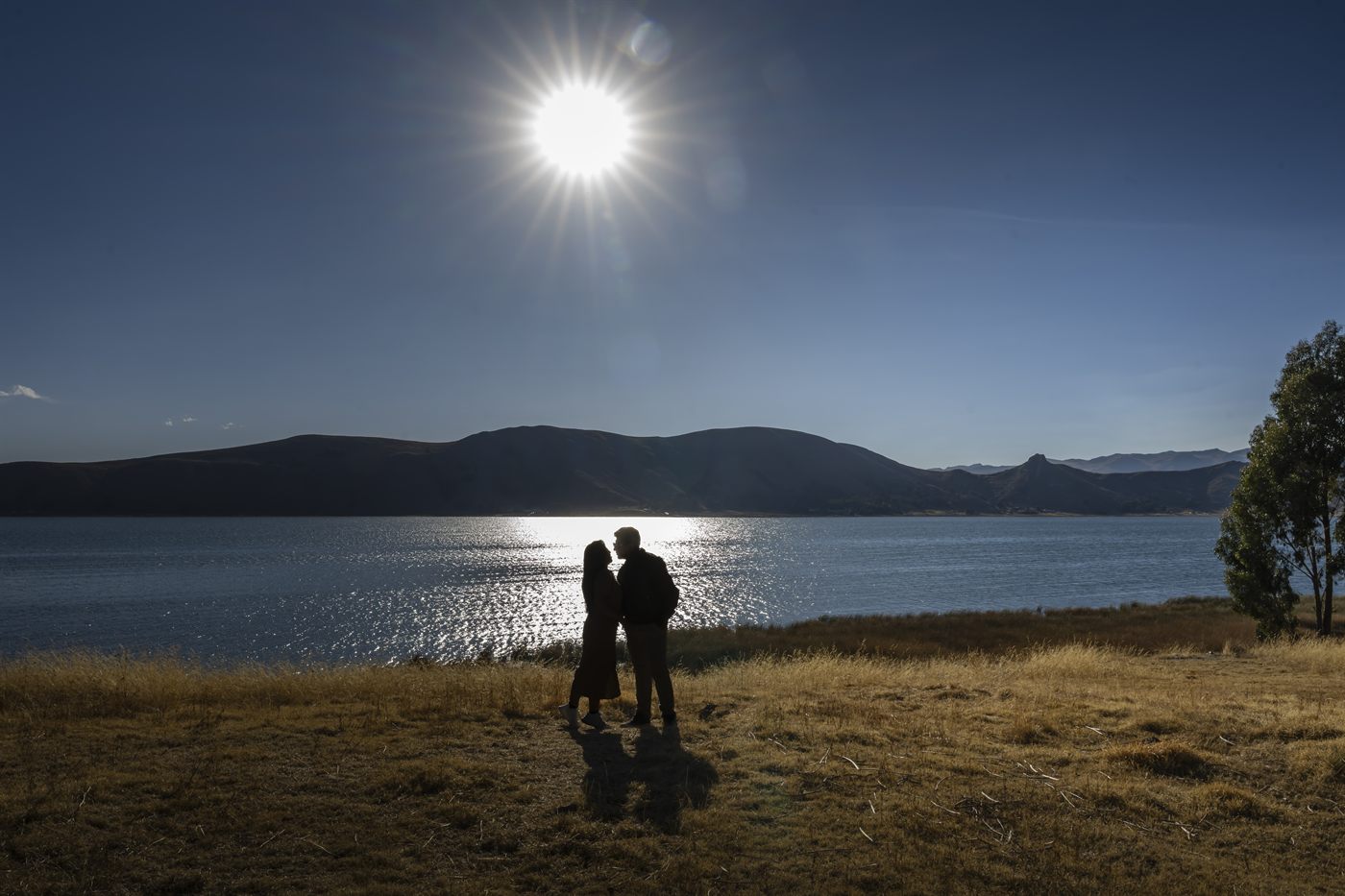 Silueta de los novios frente al lago bajo el sol